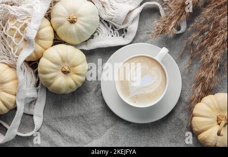 Citrouilles blanches, café et pampas sur fond textile gris. Décoration automnale. Banque D'Images