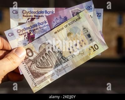 Dix et vingt livres sterling de monnaie papier de la Banque d'Écosse ont été détenus dans une main gauche de l'homme. Banque D'Images