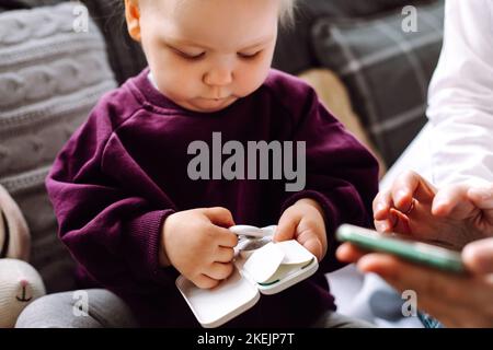Portrait d'une petite fille tenant une boîte avec thermomètre numérique mesurant la température, envoyant des informations au smartphone. Banque D'Images