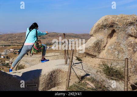 UCHISAR, TURQUIE - 4 OCTOBRE 2020 : une jeune femme non identifiée tente de capturer un cliché inhabituel du paysage de la Cappadoce depuis le sommet d'une cli tuff Banque D'Images