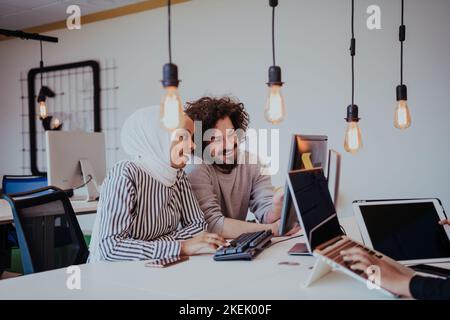 Une femme musulmane afro-américaine discute d'un projet avec un ami dans un bureau moderne Banque D'Images