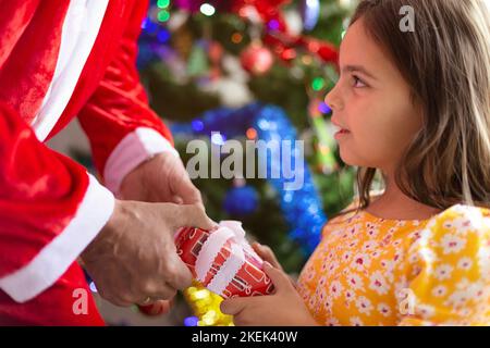 Gros plan de la petite fille recevant un cadeau du Père Noël. Noël. Banque D'Images