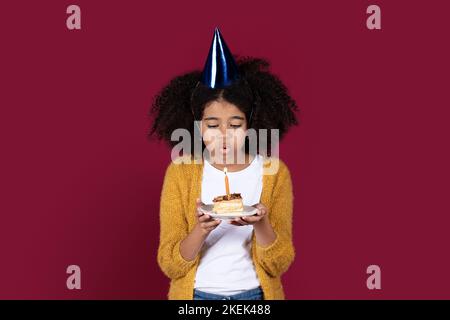 Jolie fille d'adolescent noire ayant la fête d'anniversaire, la bougie de soufflage Banque D'Images