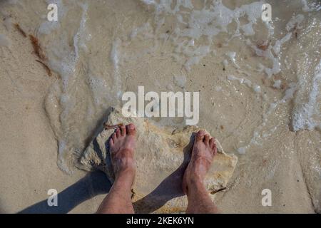 Vue sur les jambes des hommes sur l'océan Atlantique pendant la vague. Concept de vacances d'été. Aruba Banque D'Images