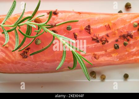 Morceau de saumon. Morceau de poisson frais de saumon cru sur un support en marbre avec des herbes et du citron sur fond noir. Concept de fruits de mer ou de menu. Vue de dessus. Banque D'Images