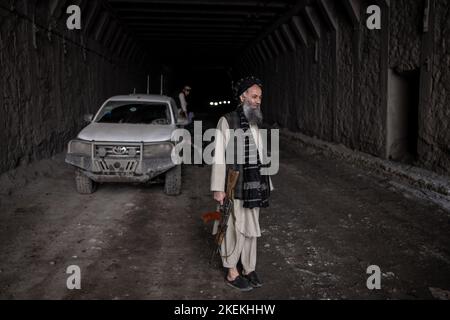 Col de Salang, Afghanistan. 13th novembre 2022. Un membre des Taliban, armé d'un fusil d'assaut AK-47, attend qu'un homme monte des chaînes antidérapantes sur son véhicule dans le tunnel de Salang tout en traversant l'Hindu Kush sur le col de Salang, le premier col de montagne reliant le nord de l'Afghanistan à la province de Parwan, avec des connexions vers la province de Kaboul. Credit: Oliver Weiken/dpa/Alay Live News Banque D'Images