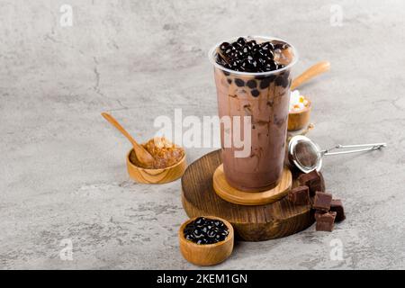 Boba ou perles de tapioca est le thé de lait à bulles de taïwan dans une tasse en plastique avec saveur de chocolat sur fond de texture, rafraîchissement d'été. Banque D'Images