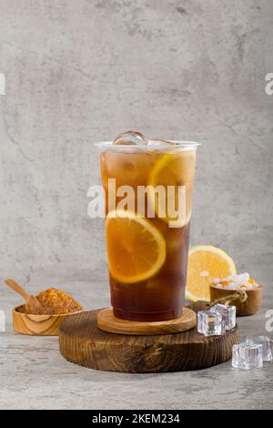 thé de limonade sucré dans une tasse en plastique avec glacés sur fond de texture, rafraichissement d'été. Banque D'Images