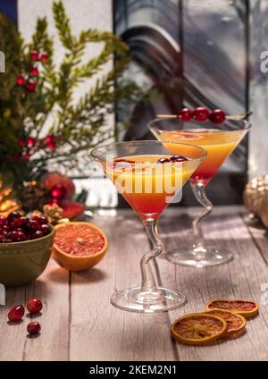 Deux mimosas de fête aux canneberges et à l'orange, garnies de tranches d'orange séchées. Banque D'Images