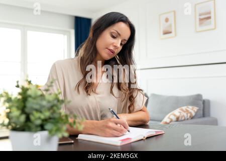 Belle et attrayante femme brune travaillant à la maison, des tâches de planification. Banque D'Images