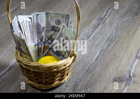 Panier en osier avec billets de cent dollars américains et citron à l'intérieur sur une table en bois gris. Concept bancaire et financier Banque D'Images