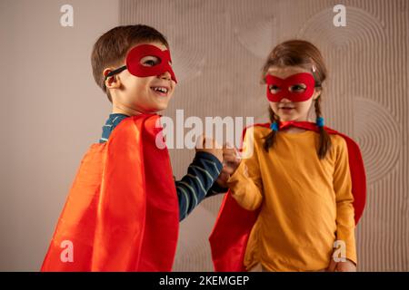 Portrait d'une équipe de deux jeunes super-héros, frère et sœur, sur fond beige. Enfant super-héros. Super héros gamin jouant à la maison. Idée, liberté Banque D'Images