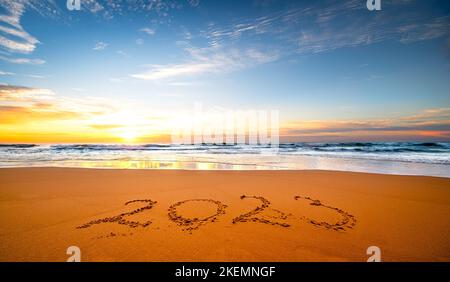 Numéro 2023 écrit sur le sable de la mer au lever du soleil. Concept de la nouvelle année à venir et du passage du temps. Banque D'Images