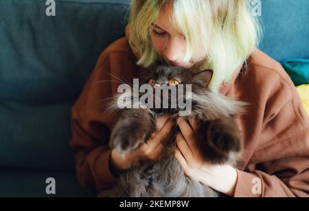 Une adolescente embrassant un chat à la maison. Banque D'Images