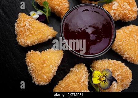 Nuggets de fromage frits avec sauce aux baies, sur fond sombre Banque D'Images