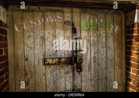 Porte d'entrepôt en bois abîmé à Bridport, Dorset avec poignées rusty Padlock et boulonné en gros plan Banque D'Images