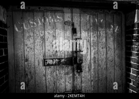 Porte d'entrepôt en bois abîmé avec poignées rusty Padlock et boulonner en gros plan. Photographie en noir et blanc Banque D'Images