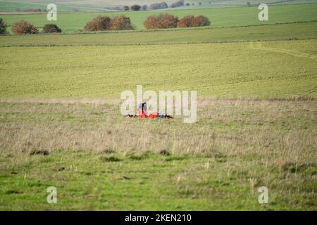 Un parachutiste rassemblant le parachute ayant atterri dans une prairie Banque D'Images