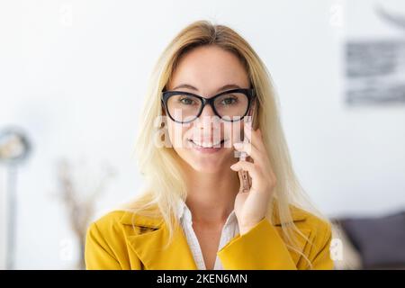 Portrait d'une femme confiante souriante et confiante, debout dans un bureau moderne, parlant sur un téléphone portable Banque D'Images