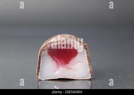 bonbons en gros plan en boîte au chocolat sur fond noir avec garniture rouge et blanche à la crème à la fraise et à la framboise. Jour bonbons au chocolat bonbons sans Banque D'Images