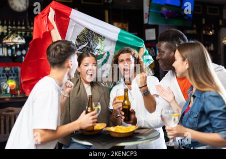 Joyeux fans de l'équipe mexicaine célébrant la victoire au bar de nuit Banque D'Images