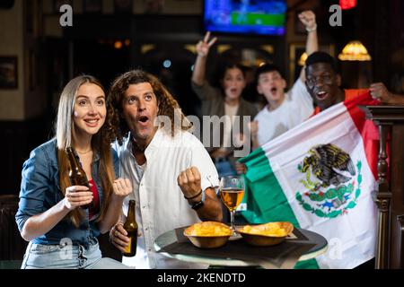 Joyeux fans de l'équipe mexicaine célébrant la victoire au bar de nuit Banque D'Images