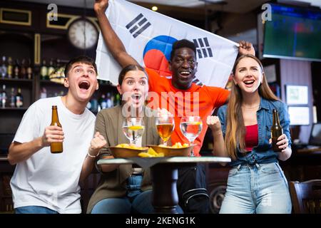 Hommes et femmes soutenant l'équipe de sports de Corée du Sud au pub Banque D'Images