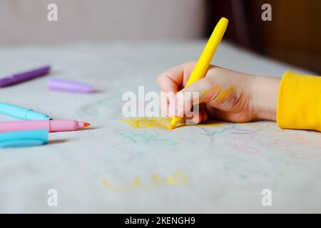 Le dessin à la main de l'enfant avec un stylo feutre rose sur la sellerie grise du canapé. La vie quotidienne taches sales pour le lavage et le concept propre Banque D'Images