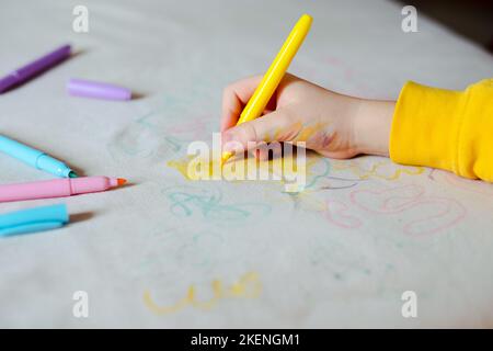 La main de l'enfant dessin avec un feutre sur la sellerie du canapé. Tissus de mobilier. Concept de nettoyage Banque D'Images