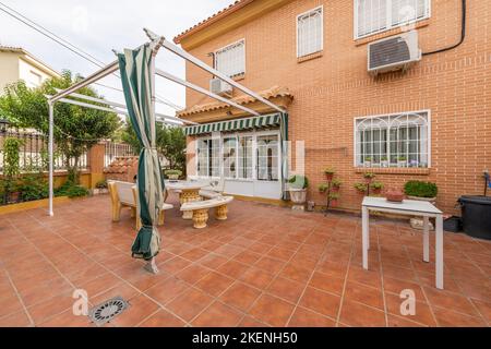 Façade d'une maison unifamiliale avec véranda avec patio carrelé et pavillon en tissu glissant Banque D'Images