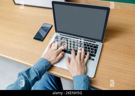 Les mains de l'homme sur le clavier d'un ordinateur portable sur une table en bois Banque D'Images