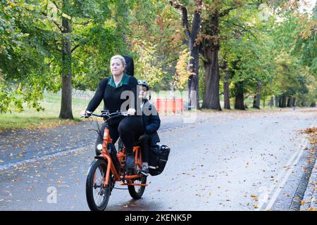 Une femme fait du vélo avec son enfant sur le siège arrière de Grrenwich Park Londres Banque D'Images