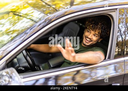 Dire bonjour. Handsome young smiling woman nouvelle voiture et en agitant son à quelqu'un. Banque D'Images