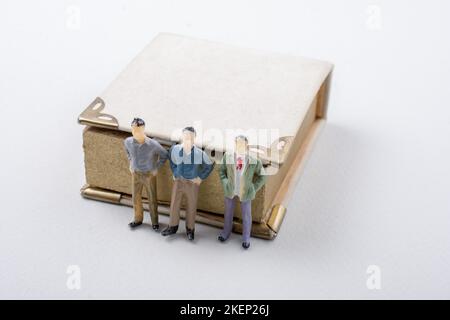 Petite figurine d'hommes modèles trouvés à côté d'un livre Banque D'Images