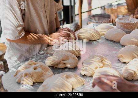 Un boulanger expérimenté à l'ombre prépare la pâte avec de la farine de haute qualité pour faire du pain biologique. Banque D'Images