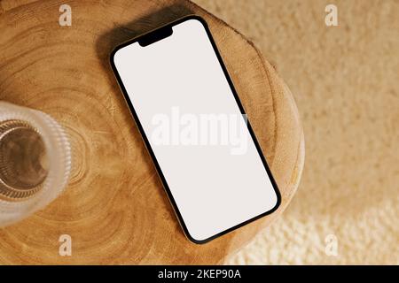 Maquette de smartphone moderne, téléphone portable avec écran blanc vide sur la table en bois, vue du dessus Banque D'Images