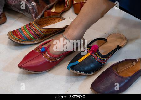 Belle femme indienne essayant son pied pour l'installation de chaussures colorées pour femmes Rajsathani à la boutique de chaussures au célèbre marché de Sardar et Ghanta ghar. Banque D'Images