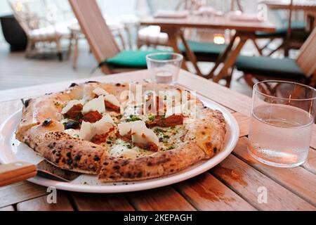 Une pizza margherita moderne au feu de bois sur une table en plein air - dîner en plein air sur le toit-terrasse restaurant et bar italien de style Naples à Hong Kong Banque D'Images