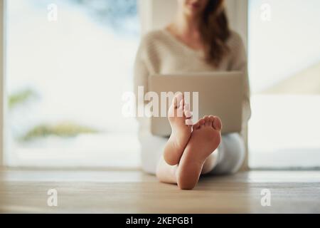 Le temps que vous aimez perdre n'est pas perdu de temps. Une jeune femme utilisant son ordinateur portable à la maison. Banque D'Images