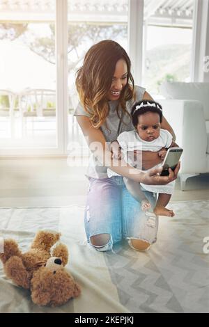 Elle ressemble à sa mère. Une mère qui parle selfies avec sa petite fille à la maison. Banque D'Images