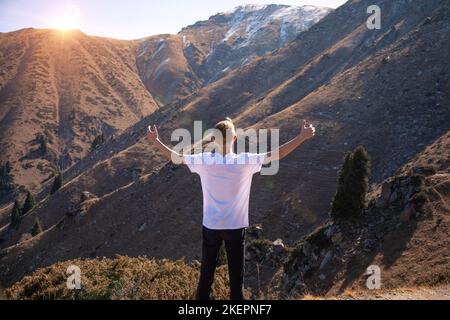 Le jeune voyageur salue le soleil dans les montagnes. Banque D'Images