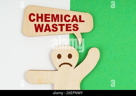 Concept environnemental. Sur fond vert et blanc, une triste figure en bois d'un homme et une plaque avec l'inscription - déchets chimiques Banque D'Images