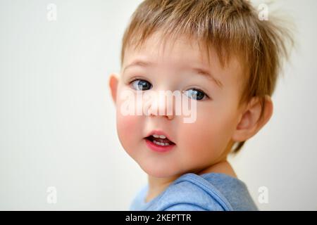 Portrait d'un bébé garçon sur l'arrière-plan d'une chambre à la maison. Le visage d'un enfant avec des cheveux au lave-vaisselle dans la pépinière Banque D'Images