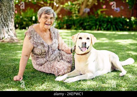 Il garde mes orteils. Portrait d'une femme âgée assise à l'extérieur avec son chien. Banque D'Images