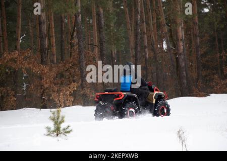 un homme méconnaissable fait du quad tout-terrain dans une forêt enneigée. Divertissement actif, extrême, adrénaline. Temps glacial Banque D'Images