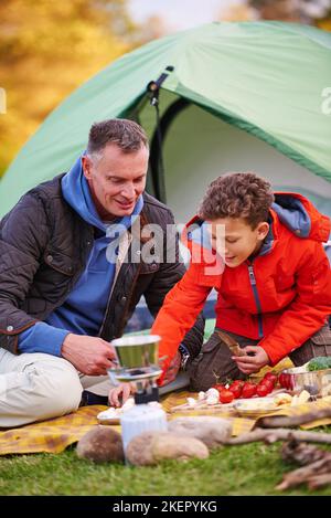 Une alimentation saine en plein air. Un père et un fils préparent un repas en campant. Banque D'Images