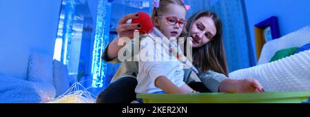 Enfant avec un handicap physique dans la chambre stimulante sensorielle, snoezelen. Enfant vivant avec une paralysie cérébrale interagissant avec son thérapeute pendant la thérapie Banque D'Images