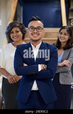 Confiant, heureux jeune entrepreneur et ses collègues derrière Banque D'Images