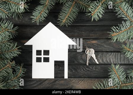 Maison en papier blanc avec clés comme cadeau de noël en famille, vue du dessus. Cadre en branches d'épicéa biologique. Acheter de nouveaux biens immobiliers. Noël ou nouvel an Banque D'Images