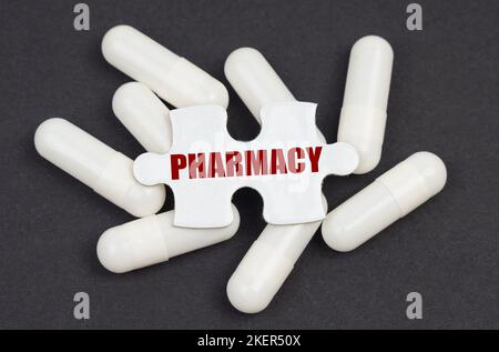 Concept de médecine. Sur fond noir, des capsules et un puzzle avec l'inscription - PHARMACIE Banque D'Images